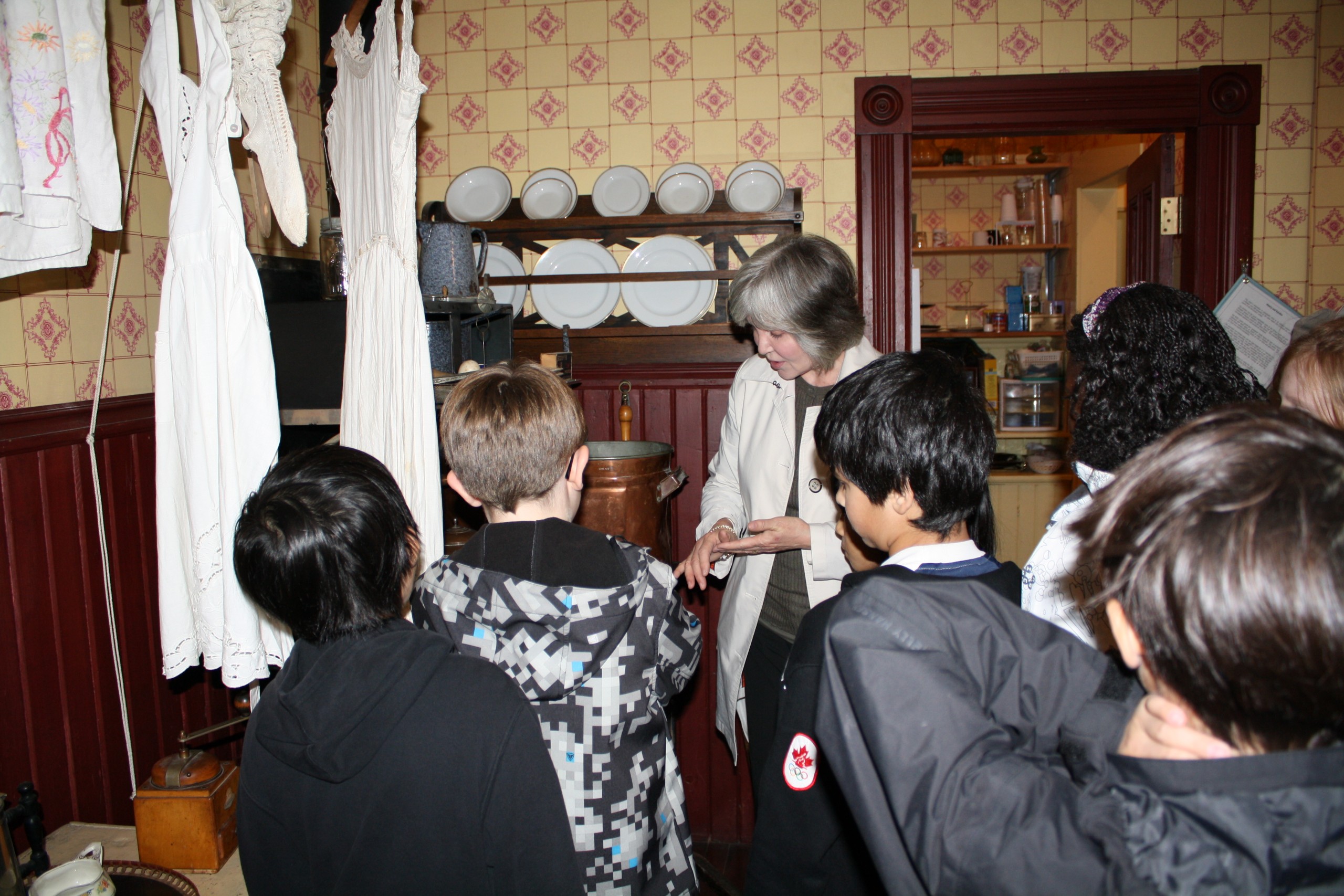 A woman shows children the historic kitchen.